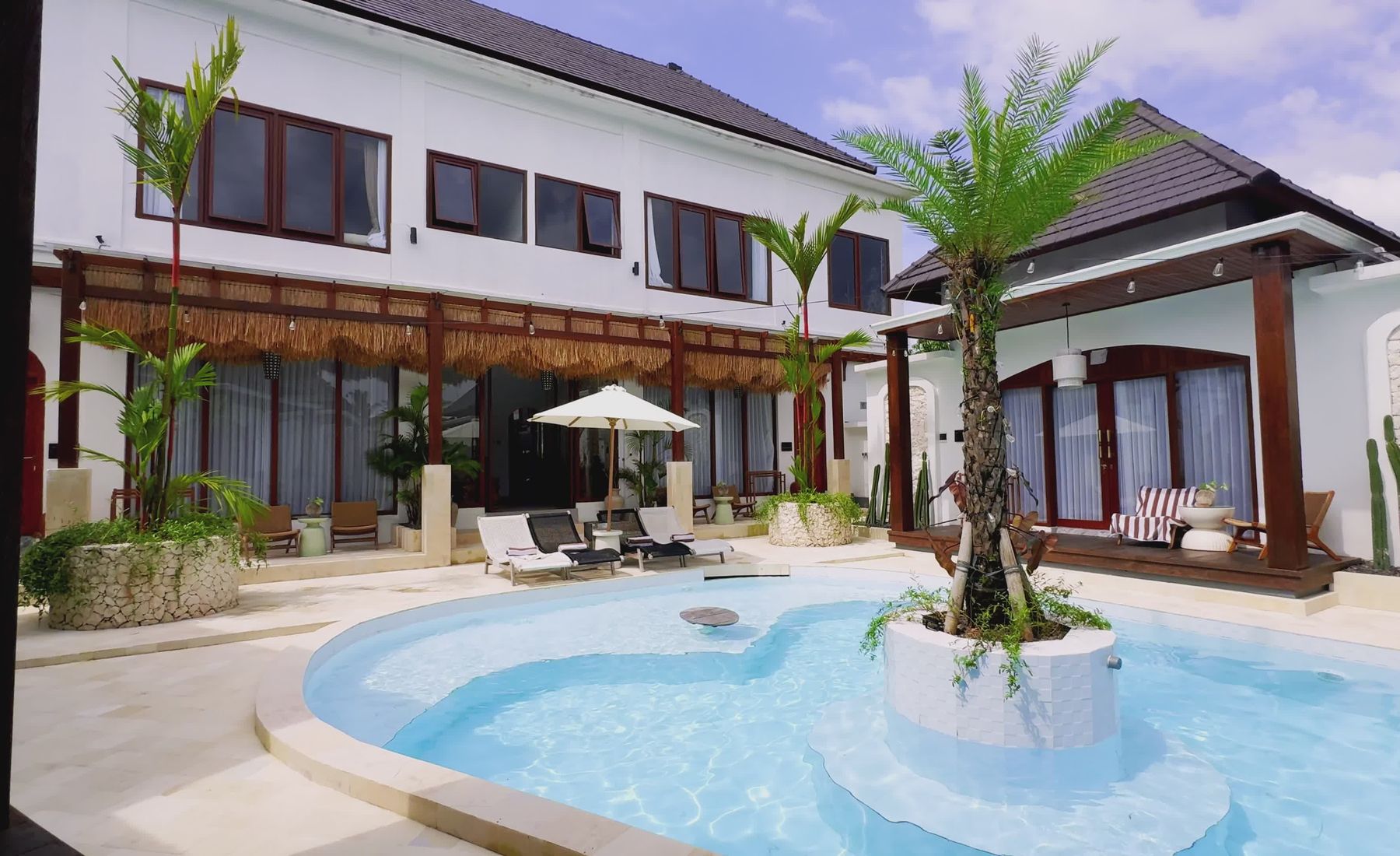 Une villa tropicale ouverte sur une piscine et la végétation